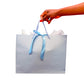 A light blue gift bag with light blue rope handles and a light blue satin ribbon bow, held by a person's hand against a white background.